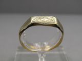 une image montrant un gros plan d'une bague en or posée sur une surface transparente