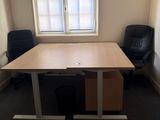 a desk with two chairs in front of a window