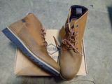 pair of men ' s brown boots sitting on top of a cardboard box