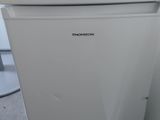 a small white refrigerator in the corner of a room