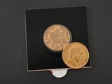 two gold coins sitting next to each other on a black surface