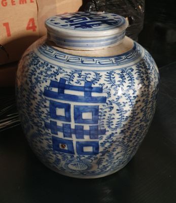 un vase bleu et blanc posé sur une table, avec une boîte en arrière-plan