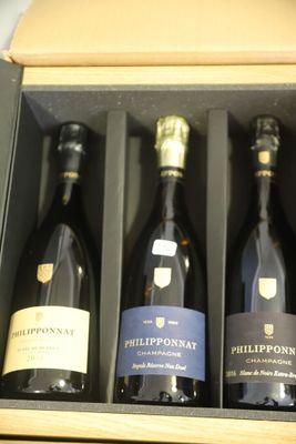 Il y a trois bouteilles de vin dans une boîte posée sur une table