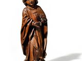 an old wooden statue of a man with a hat and robe