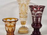 three different colored glass vases sitting next to each other on a white surface