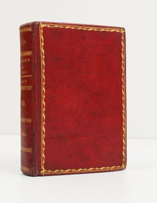 un vieux livre rouge posé sur une table blanche