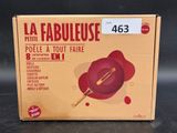 emballage d'une poêle rouge sur laquelle est posée une spatule en bois