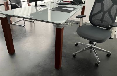 a glass desk with a chair and a computer on it