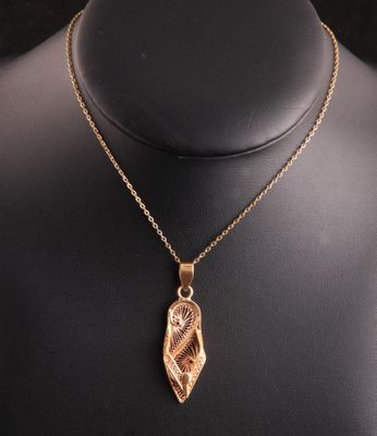a gold plated necklace with a leaf pendant on a mannequin