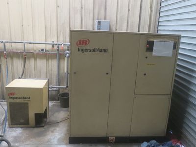 two air compressors in a storage room next to each other