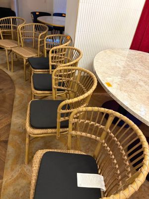 plusieurs chaises en osier et une table dans une pièce ornée d'un rideau rouge