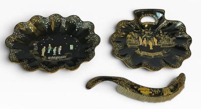 deux assiettes noires et dorées et une cuillère posées sur un plan de travail blanc