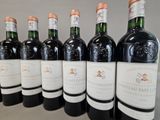 six bottles of wine are lined up on a table