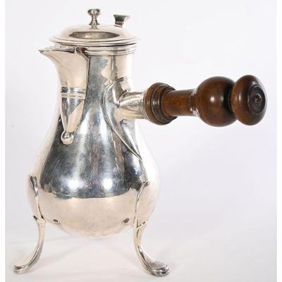 une cafetière en argent avec une poignée en bois, posée sur un socle