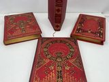 trois livres rouges ornés de bordures dorées et de motifs décoratifs