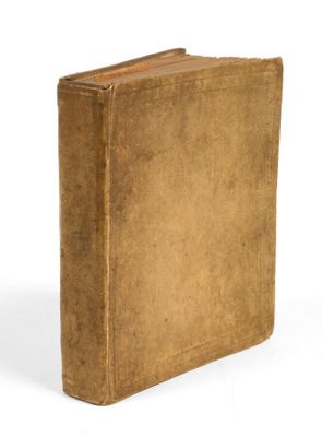 un vieux livre brun posé sur une surface blanche