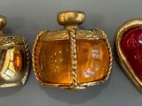 trois flacons de parfum en verre doré et rouge posés sur une table