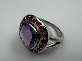 a close up of a ring with a purple stone surrounded by red stones