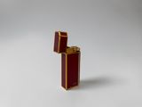 a red and gold lighter sitting on top of a white surface