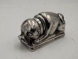 a silver figurine of a dog that is laying down