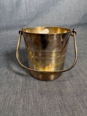 an antique brass bucket with handles on a grey background