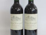 two bottles of red wine sitting next to each other on a white surface
