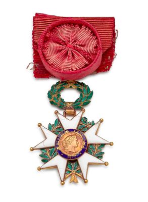 Gros plan sur une médaille sur fond blanc, accompagnée d'un ruban rouge