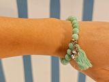 someone is wearing a bracelet with a green tassel on it