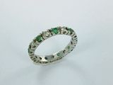 a close up of a ring with green stones on a white surface