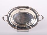 un plat ancien en argent posé sur un socle et entouré d'une chaîne