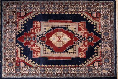 un tapis ancien aux motifs rouges, bleus et beiges