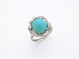 une bague ornée d'une pierre turquoise et de diamants, sur fond blanc