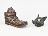 deux figurines représentant un chat et une chaussure posées sur une surface blanche