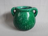 un vase vert posé sur une surface blanche