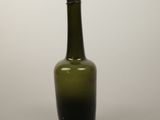 a green glass bottle sitting on a white surface