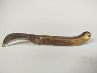 une image représentant un couteau en bois muni d'un long manche, posé sur une surface blanche