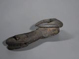 an old wooden shoe with a metal handle on a gray surface