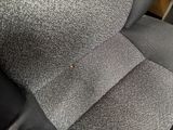 the back of a gray couch with a pillow and a button on it