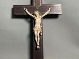 une croix en bois surmontée d'un crucifix, sur fond gris