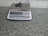 une balance électronique posée sur un comptoir, sur laquelle se trouve un chargeur