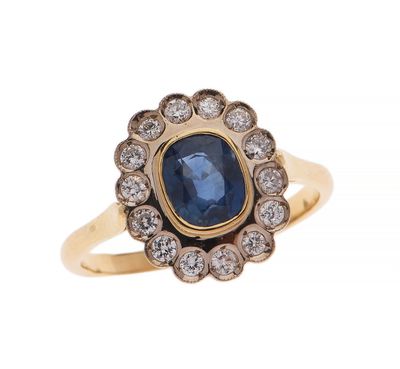 gros plan d'une bague en or avec un saphir et des diamants