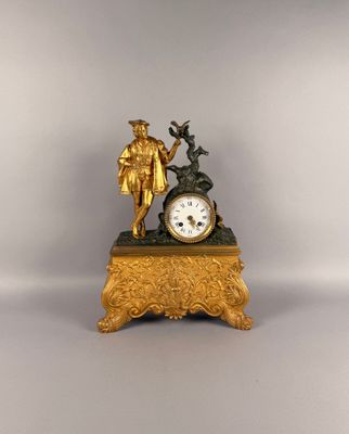 une horloge en or surmontée d'une statue représentant un homme et une femme