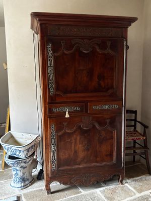 une armoire en bois dans un coin de la pièce, à côté d'une chaise