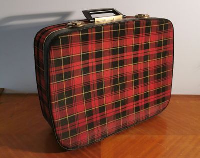 a red and black plaid suitcase sitting on a wooden table