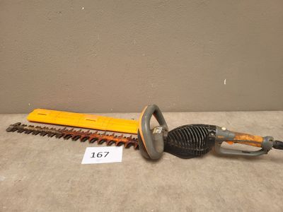 un gros plan d'une tondeuse à haies filaire posée sur une table, à côté d'une règle