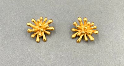une paire de boucles d'oreilles en or posées sur une surface grise