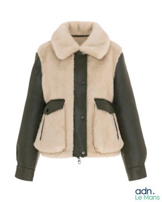 La veste est noire et blanche, avec un col en fourrure.