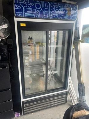 une photo d'un réfrigérateur dans un garage, avec un ventilateur