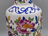 un vase blanc orné de fleurs colorées, posé sur une table