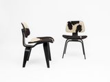 a pair of black and white chairs with a cow hide on them